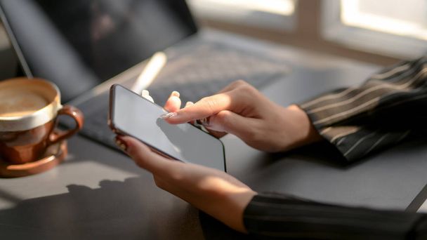 Plan recadré de femmes d'affaires envoyant des textos sur un smartphone à écran blanc dans une pièce de bureau sombre moderne
 - Photo, image
