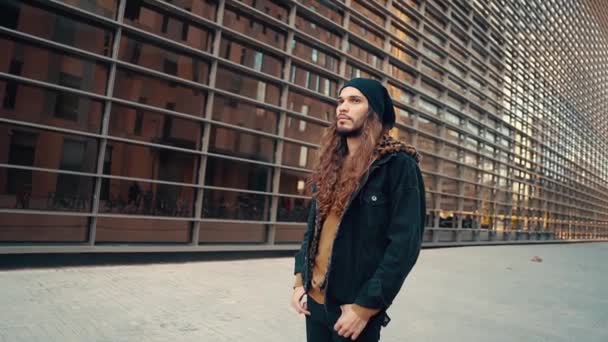 Porträt eines langhaarigen Hipsters, der in der modernen Stadt auf der Straße läuft - Filmmaterial, Video