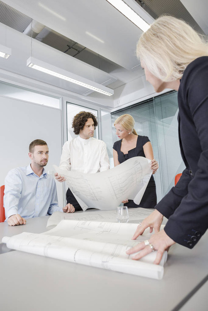 Colleagues discussing blueprints in office - Fotografie, Obrázek