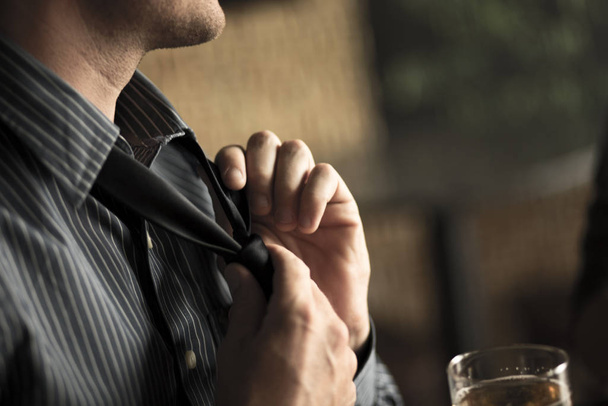 Close up of businessman loosening tie in a wine bar - Foto, afbeelding