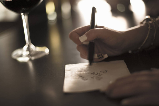 Close up of young woman writing her phone number on a napkin in bar - Valokuva, kuva