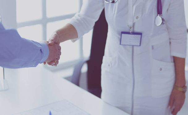 Female doctor handshaking a patients hand and smiling - Foto, afbeelding