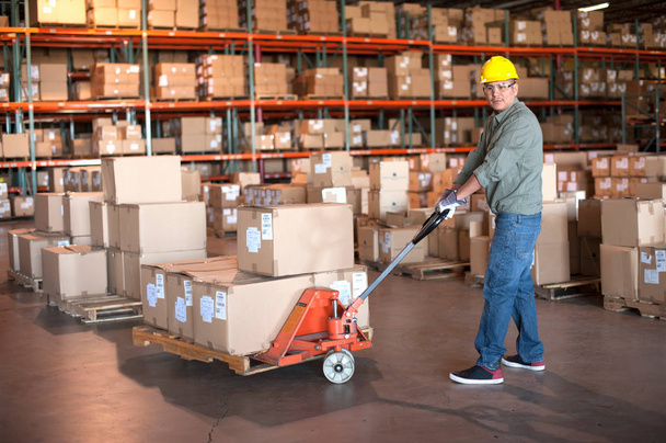 Male warehouse worker operating pallet jack - Foto, immagini