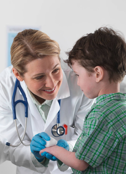 Arzt versorgt kleinen Jungen mit Verletzungen - Foto, Bild