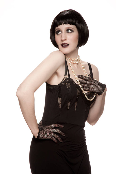 Mid adult woman in 1920's style black dress against white background - Photo, image