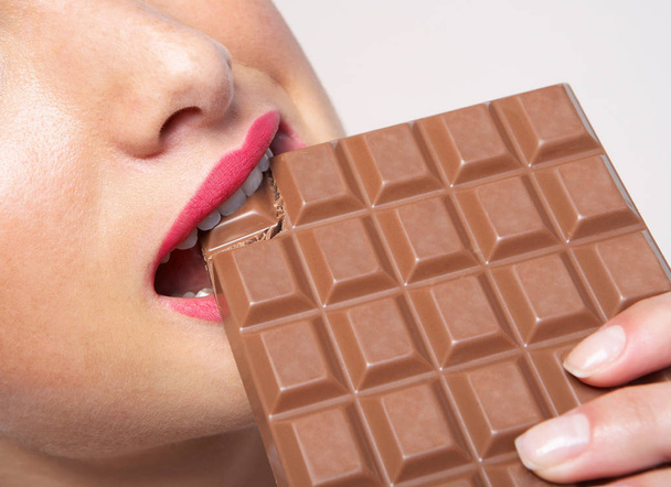 Woman biting huge bar of chocolate - Zdjęcie, obraz