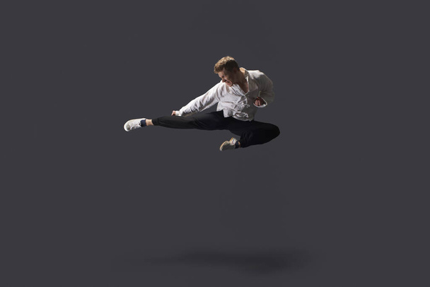 Studio shot of young man mid air practicing martial arts - Foto, afbeelding