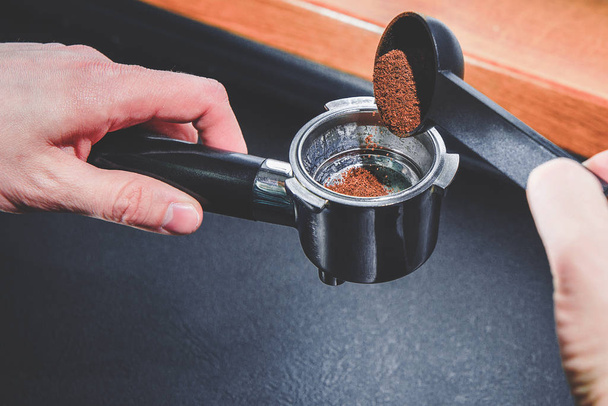 Préparation du café. L'homme tient un moulin à café dans sa main et le remplit de café moulu. C'est l'heure de la pause, du café. Café noir moulu, machine à café
. - Photo, image