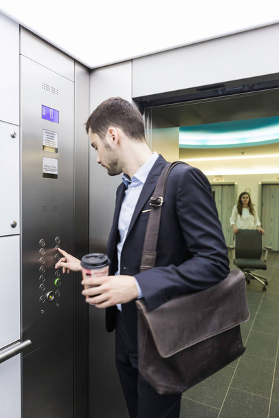 Podnikatel stiskne tlačítko ve výtahu - Fotografie, Obrázek