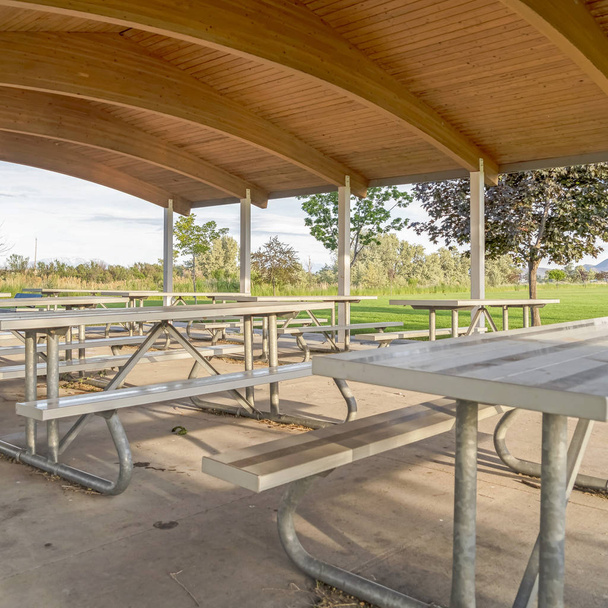 Plac Miejsce do jedzenia w parku ze stołami i miejscami pod brązowym drewnianym dachem pawilonu - Zdjęcie, obraz