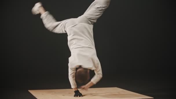 Jongeman danser draait rond leunend op zijn handen op de houten plank - Video
