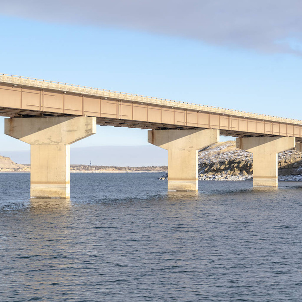 Square Stringer most přes modré jezero a spojující zasněžené skalnaté terény - Fotografie, Obrázek