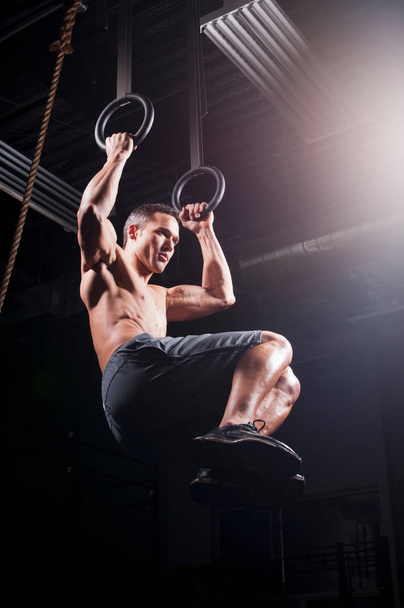 Man using suspended rings in gym - Photo, image