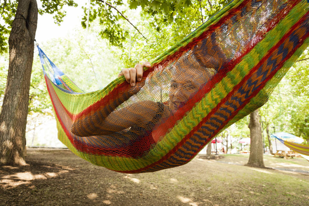 Portrait of mid adult woman lying in park hammock - 写真・画像