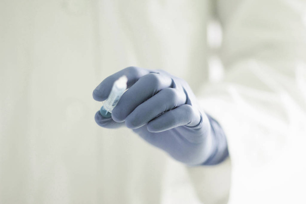 Gloved hand holding syringe - Фото, изображение