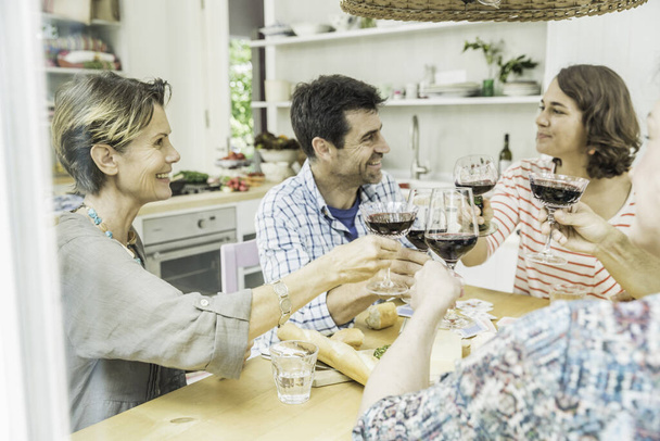 Adult friends making a toast with wine at dining table - Фото, зображення