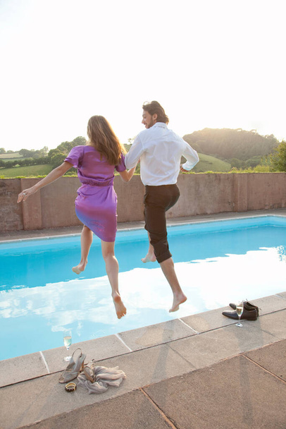 couple jumping into pool,dressed - Photo, Image