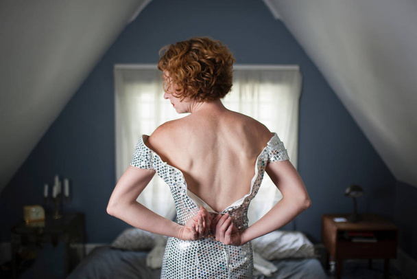 Woman in bedroom unzipping evening gown - Foto, immagini