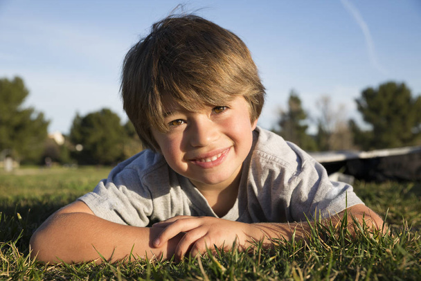 Portrait of smiling boy lying on park grass - Foto, immagini