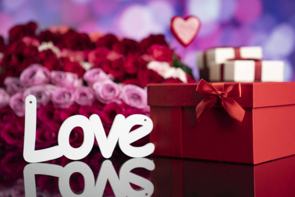 Valentin napi fogalom. Ajándékok dobozokban, vörös szívek és nagy csokor természetes rózsa kék bokeh háttér. - Fotó, kép