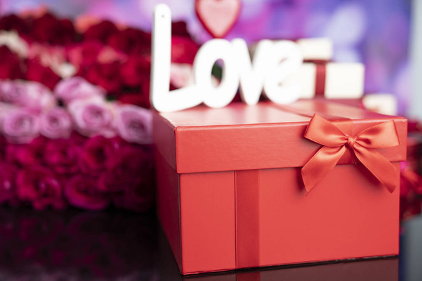 Valentines day concept. Gifts in boxes, red hearts and big bouquet of natural roses on blue bokeh background. - Photo, Image