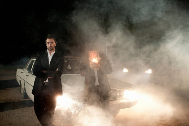 Men in suits waiting by car in fog - Foto, Bild