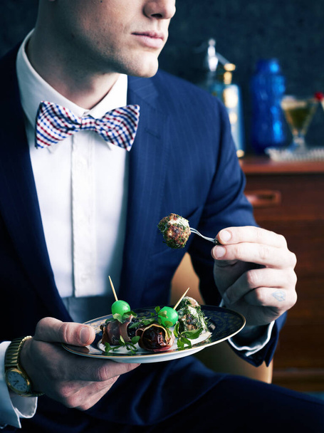Retro styled man eating plate of appetizers - 写真・画像