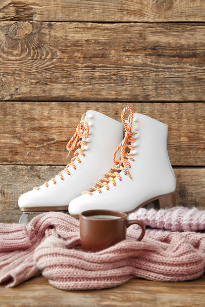 Zapatillas de patinaje sobre hielo con ropa y taza de café sobre fondo de madera
 - Foto, imagen