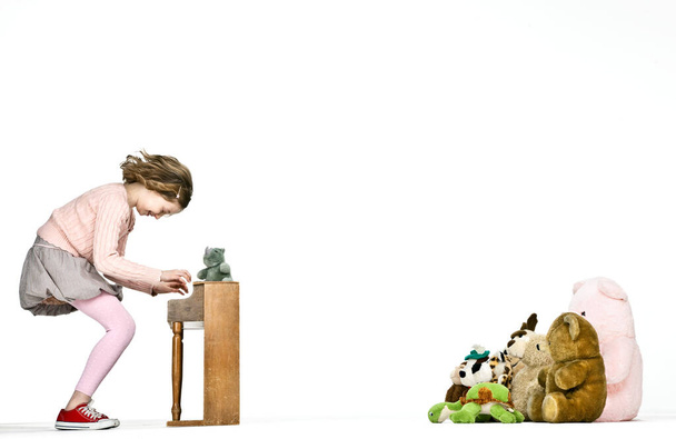 Girl playing miniature piano for teddy bears - Zdjęcie, obraz