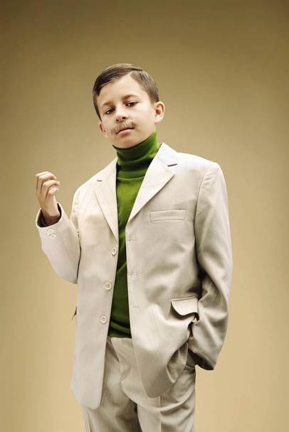 Young boy dressed in beige suit with fake mustache - Fotoğraf, Görsel