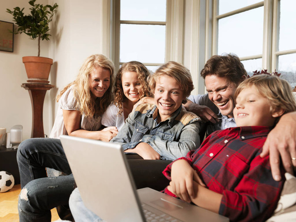 Family watching laptop together on sofa - Foto, imagen