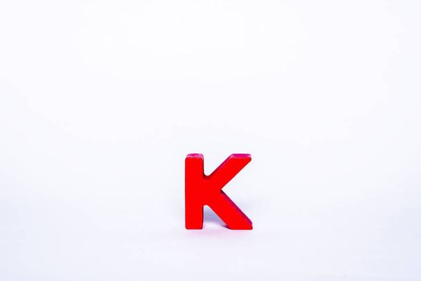 Uma única letra vermelha K num fundo branco. Alfabeto de madeira isolado letra
. - Foto, Imagem