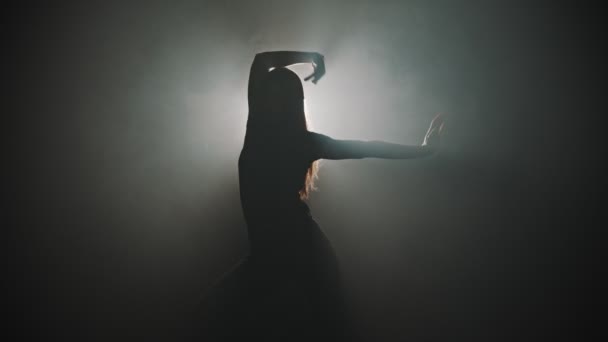 Een silhouet van jonge aantrekkelijke vrouw dansen met haar handen op de achtergrond van heldere verlichting - Video