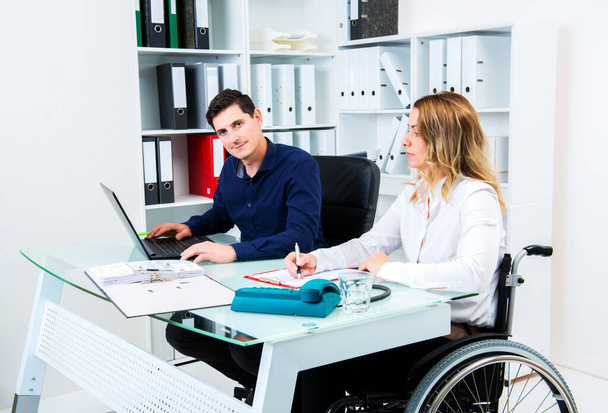 disabled businesswoman in wheelchair and her colleague in the office - Fotoğraf, Görsel