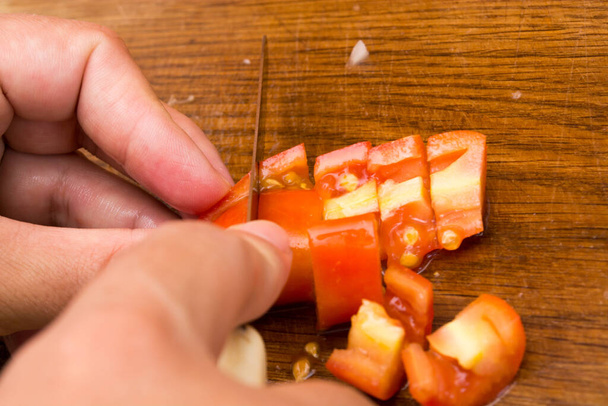 Резать и рубить помидоры на деревянной тарелке. Подготовка к салату
 - Фото, изображение