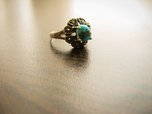 Niebieski turkus pierścień pierścień damski. Srebrny pierścionek ozdobiony niebieskim turkusowym kamieniem. Muzułmanie używają go jako Świętego kamienia. Turkusowy pierścień na ciemnym drewnianym tle - Zdjęcie, obraz