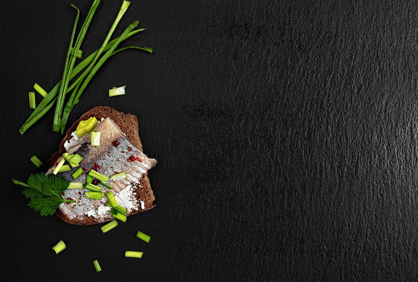 Haring sandwich (traditionele Deense smorrebrod) op de zwarte achtergrond. Bovenaanzicht met kopieerruimte. Gezond voedsel. - Foto, afbeelding