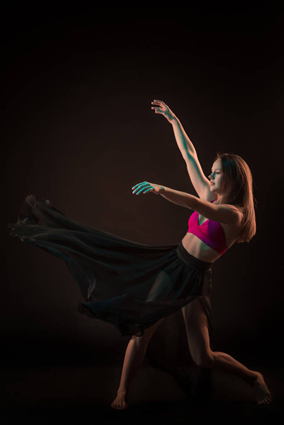 Молодий красивий танцюрист у бежевій сукні танцює на чорному студійному фоні
 - Фото, зображення