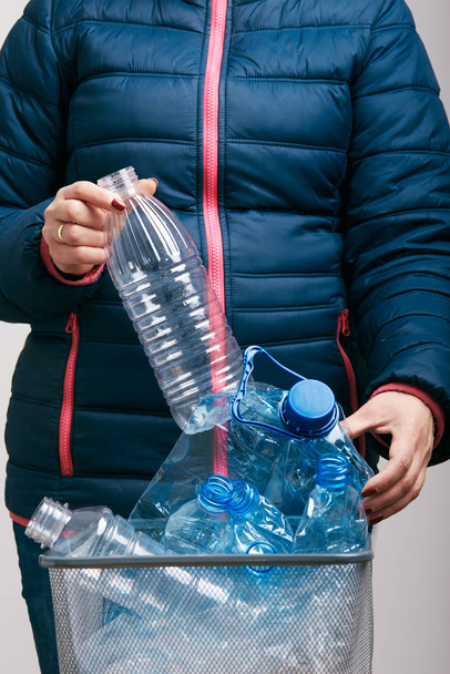 Woman collecting used plastic bottles and packagings in trash - Fotó, kép
