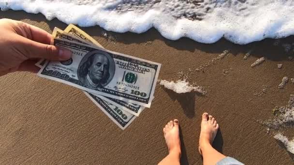 Chica sosteniendo la factura de dinero de 300 dólares en el fondo de las olas del mar
 - Metraje, vídeo