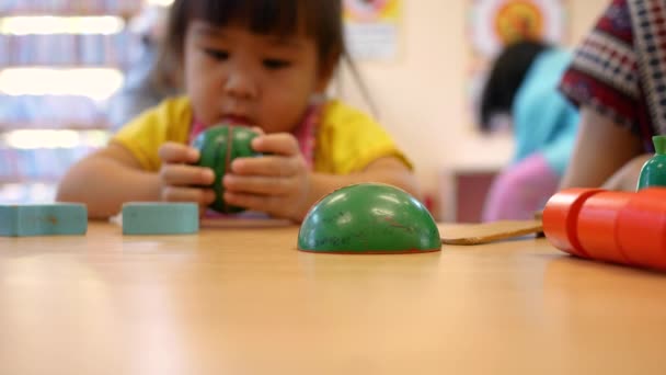Симпатична маленька дівчинка розважається, граючи з кулінарними іграшками у вітальні в класі. Малюк використовує дерев'яний іграшковий ніж для нарізання овочів на дерев'яну дошку. Концепція освітніх іграшок для молодої чилі
 - Кадри, відео