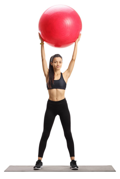 Young female in sportswear exercising with a fitness ball  - Фото, изображение