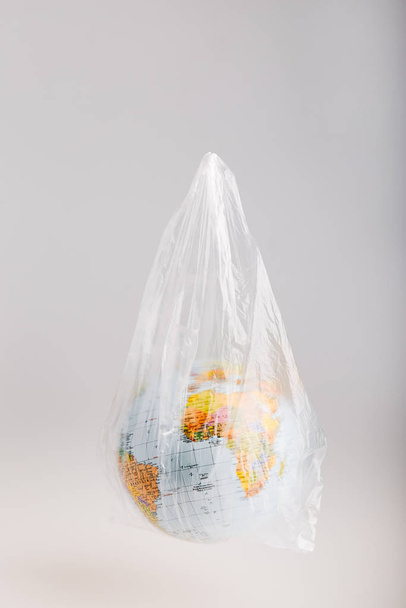 Globe in a plastic bag. Earth contaminated by plastic waste - Foto, Imagen