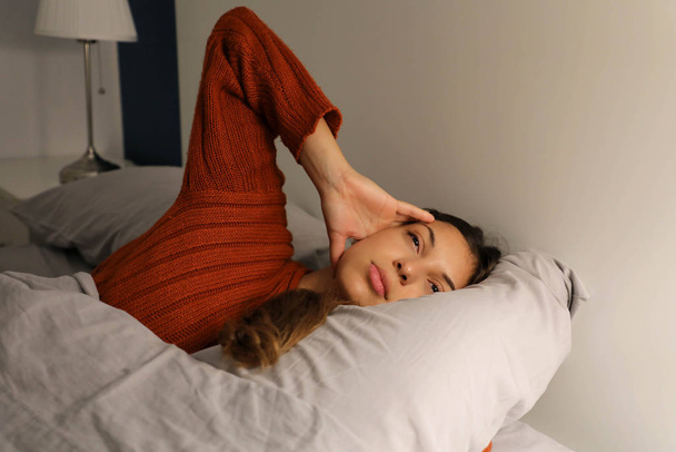 Jovem na cama sofrendo de insônia de dor de cabeça por estresse enxaqueca
 - Foto, Imagem