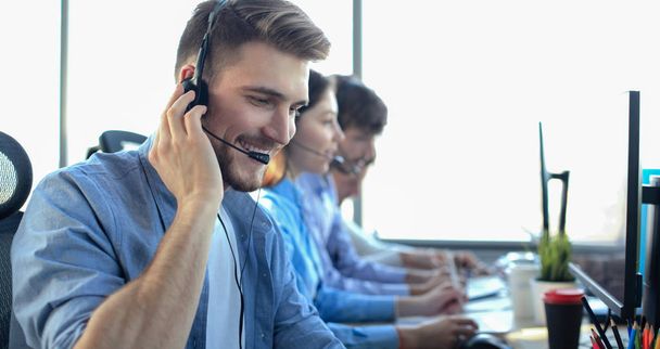 Portrait of call center worker accompanied by his team. Smiling customer support operator at work. - Foto, Imagem