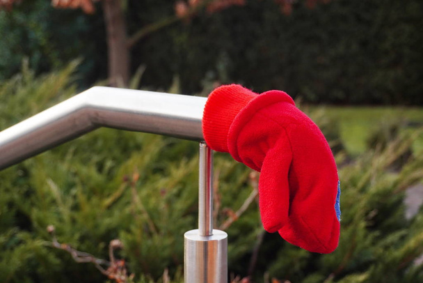 A red child's little glove or mitten is lost and lies on a shiny - Photo, Image