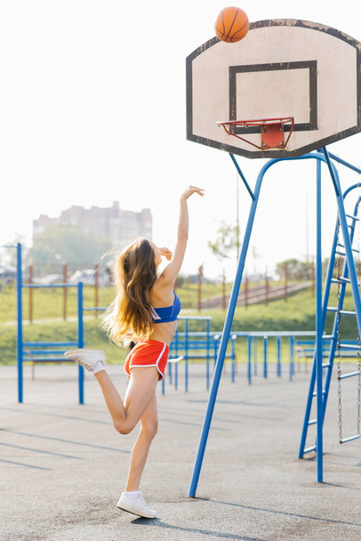 A beautiful athletic slender girl plays basketball on the Playgr - Foto, afbeelding