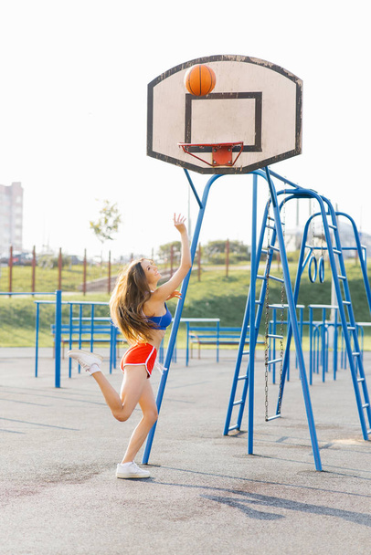 Une belle fille athlétique mince jette un ballon de basket dans le r
 - Photo, image