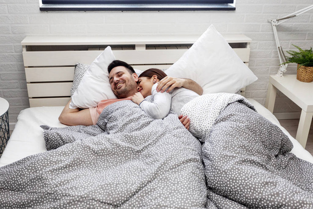 Nuori pari makaa sängyssä aamulla
 - Valokuva, kuva