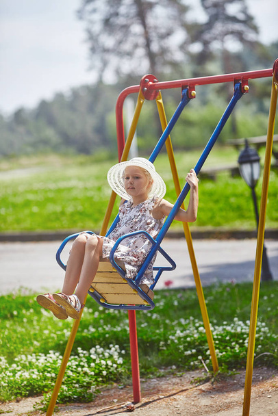 Menina bonito balançando no teeter-totter no parque infantil
 - Foto, Imagem